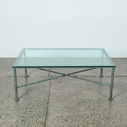 A Steel Coffee Table with a Cross Bare Base with a Glass Top