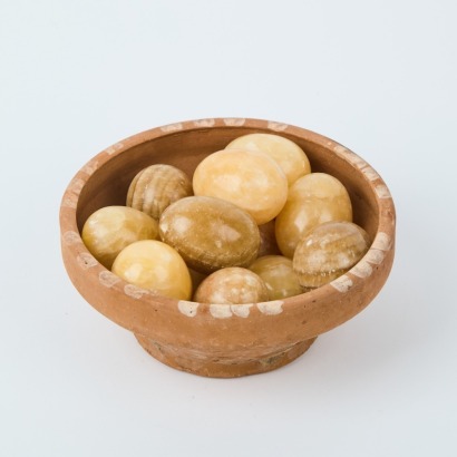 A Dozen Soapstone Eggs In A Terracotta Bowl