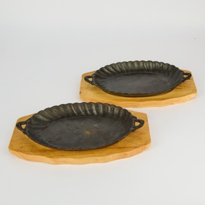 A Pair of Scolloped Edge Cast Iron Sizzle Plates With Wooden Boards