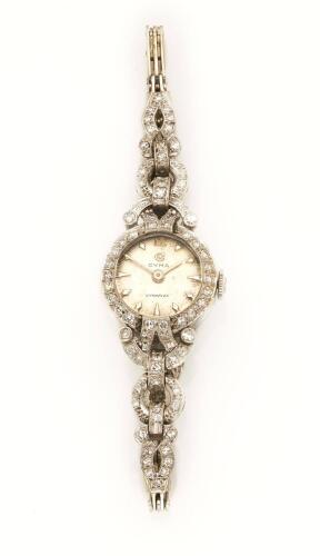 A Lady's gold and diamond cocktail wristwatch, Cyma, circa 1960's. Manual. 17mm. Circular case, silvered dial with applied baton numerals. Diamond set bezel, lugs and 9ct white gold bracelet. 18ct white gold and platinum. Weight 19.74 grams. Gemmologist's