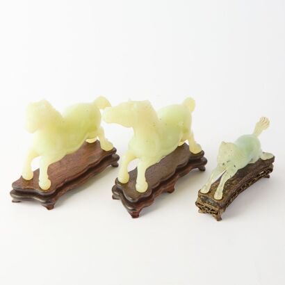 A Group of Three Chinese Green Jade Horse Carvings with Wooden Stands
