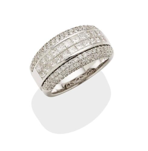 A diamond band ring, the wide band set with a central panel of twenty-two princess cut diamonds, within a pave diamond surround. 18ct white gold. Weight 12.09 grams. Size N.