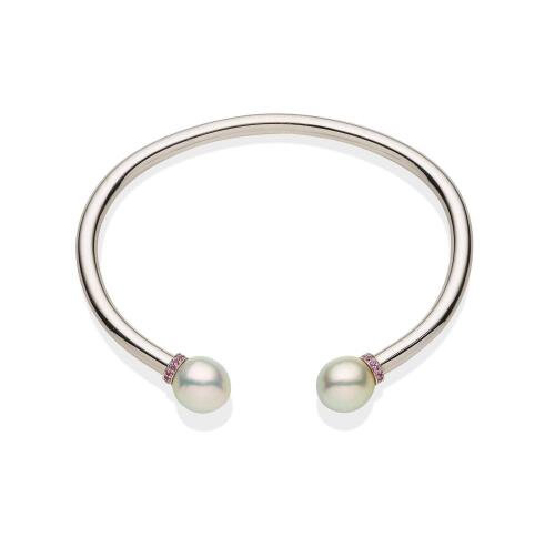 A South Sea pearl and sapphire bangle, the plain polished bangle with pink sapphire rondels and off-round pearl terminals measuring 10.5 - 11mm. 9ct white gold. Weight 37.98 grams. Inside width 7cm.&nbsp;