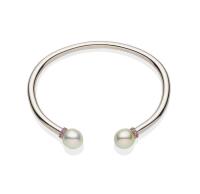 A South Sea pearl and sapphire bangle, the plain polished bangle with pink sapphire rondels and off-round pearl terminals measuring 10.5 - 11mm. 9ct white gold. Weight 37.98 grams. Inside width 7cm. 