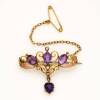 An Edwardian amethyst and seed pearl bar brooch, of filigree design and supporting a heart-shaped amethyst drop. 9ct rose gold. Weight 3.66 grams. Length 3.5cm.