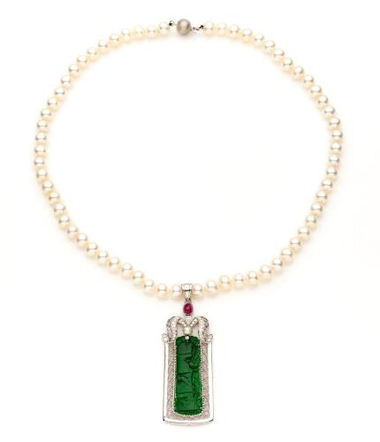 A jade, ruby, diamond and pearl pendant, the rectangular carved jade panel in pierced surround, with a scrolling diamond and ruby set surmount, hung on a freshwater pearl necklace. White gold. Pendant length 5cm.