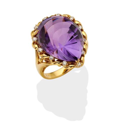 An amethyst and diamond cocktail ring, the fancy cut pear-shaped amethyst in a pierced diamond set surround. Known total diamond weight 0.24 carat.  18ct yellow gold. Weight 9.95 grams. Size M.