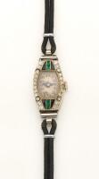 A Lady's Art Deco emerald diamond and onyx wristwatch, circa 1920's. 18mm. Tonneau shaped case set with single cut diamonds and calibre emeralds and onyx. Black strap. 18ct yellow and white gold. Please note: orginal movement has been replaced with quartz