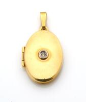 A gold and diamond locket, the front of the plain polished oval locket set with a small round brilliant cut diamond. 9ct yellow gold. Weight 3.26 grams. Length 23mm.