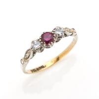 A ruby and diamond ring, the central round ruby set either side with small round brilliant cut diamond. 9ct white gold. Weight 1.45 grams. Size M.