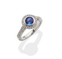 A tanzanite and diamond ring, the central round tanzanite of know weight 0.97 carat, bezel set in a diamond frame. Total known diamond weight 0.20 carat. 18ct white gold. Weight 5.10 grams. Size M. Gemmologist's report available.