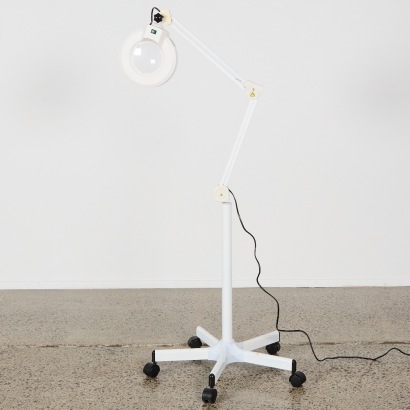A Large Magnifying Glass With Lamp On Stand With Wheels