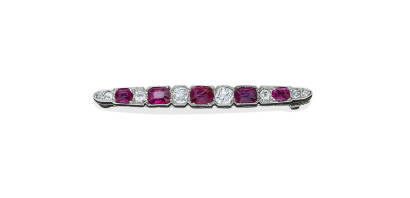 An Art Deco ruby and diamond bar brooch, the tapering bar set with eight old brilliant cut diamonds and five alternating cushion cut rubies. Estimated total diamond weight 1 carat and estimated total ruby weight 2.58 carats. Platinum. Weight 3.3 grams. Le