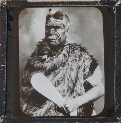 AMERICAN PHOTOGRAPHIC COMPANY (AUCKLAND) Unknown sitter with tā moko, patu and kahu huruhuru.
