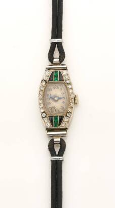 A Lady's Art Deco emerald. diamond and onyx wristwatch, circa 1920's. 18mm. Tonneau shaped case set with single cut diamonds and calibre cut emeralds and onyx. Black strap. 18ct yellow and white gold. Original movement has been replaced with quartz moveme