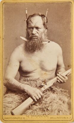 JAMES BRAGGE Two Carte de visite studio portraits. A male and female Māori subjects posing with feathers in their hair