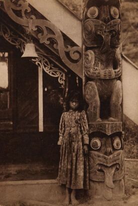 UNKNOWN PHOTOGRAPHER A French Catholic mission card with a young Māori woman standing next to the amo of Tawhitinui Wharenui
