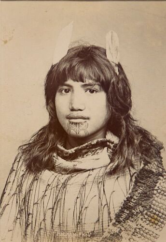 PULMAN'S PHOTOGRAPHIC STUDIO Portrait of Anie Hereni,with a moko kauae, two feathers in her hair and wearing a korowai hukahuka