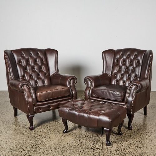 A Pair of Leather Chesterfield Wingback Armchairs and Ottoman