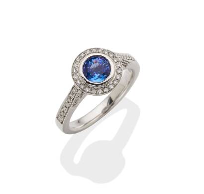 A tanzanite and diamond ring, bezel set round cut tanzanite of estimated total weight 0.97 carat, surrounded by round cut diamonds of estimated total weight 0.20 carats. 18ct white gold. Weight 5.1 grams. Size M. Gemologist's report available.