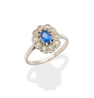 A sapphire and diamond cluster ring, claw set oval sapphire centre surrounded by ten old European cut diamonds. 18ct white gold. Weight 3.3 grams. Size O.