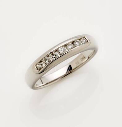 A diamond eternity ring, the front section of the band channel set with seven round brilliant cut diamonds. 18ct white gold. Weight 3.4 grams. Size L.