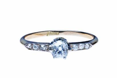 An antique solitaire diamond ring, claw set with an old mine cut diamond centre of estimated weight 0.30 carat, with diamond line shoulders. 18ct yellow gold and platinum. Weight 1.6 grams. Size L.