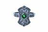 An emerald and diamond plaque ring, the pierced plaque is set with a round cut emerald centre with small round brilliant cut diamonds. 18ct white gold. Weight 6.4 grams. Size M.