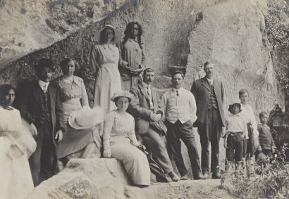 PHOTOGRAPHIC POSTCARD Figures Standing in front of rock face