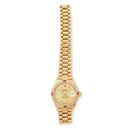 A Lady's gold Oyster Perpetual Datejust wristwatch, Rolex, circa 1980's. Automatic. 26mm. Ref: 6917/8. Serial number 6668099. Gold dial with diamond markers. Diamond and ruby set bezel. Case and dial signed. Original President bracelet numbered 8570F/68B.