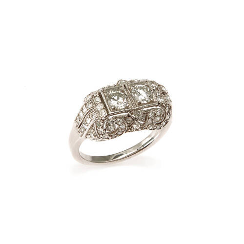 An Art Deco diamond ring, two claw set early round brilliant cut diamond centre stones of estimated total weight 0.50 carats, surrounded by seventy-four single cut diamonds of estimated total weight 0.60 carats in ornate pierced scroll setting. Platinum. 