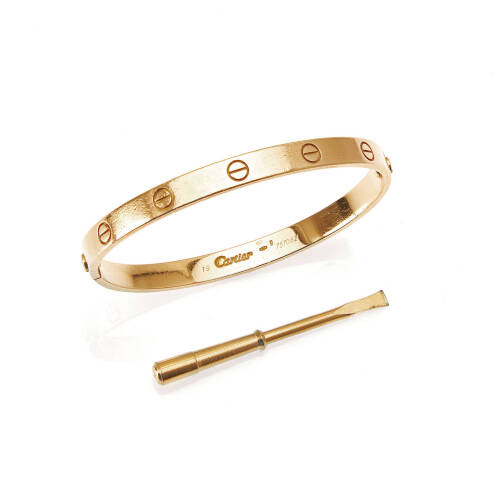 A gold Love bangle, Cartier. Serial number 757082. Front and back section of screw-on bangle decorated with screw motif. 18ct yellow gold. Weight 34.9 grams. Inside diameter 6.3cm. To be sold with gold tone screw driver.