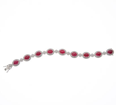 A ruby and diamond bracelet, nine cabochon cut rubies of estimated total weight 35.41 carats, surrounded by three hundred and fifteen pave set round brilliant cut diamonds of estimated total weight 2.96 carats. 18ct white gold. Weight 36.6 grams. Length 1