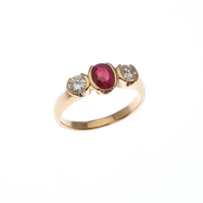 A ruby and diamond ring, semi bezel set oval cut ruby centre of estimated weight 1.0 carat, with one round brilliant cut diamond either side of estimated total weight 0.65 carats. 18ct yellow gold. Weight 6.1 grams. Ring size Q1/2. Gemologist's report ava