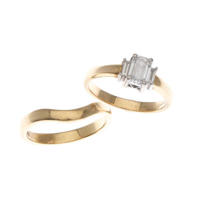 A three stone diamond ring, claw set emerald cut diamond centre of estimated weight 0.70 carat, with a baguette cut diamond set on either side of estimated total weight 0.12 carats. To be sold with fitted gold wedding ring. 18ct yellow gold and platinum. 