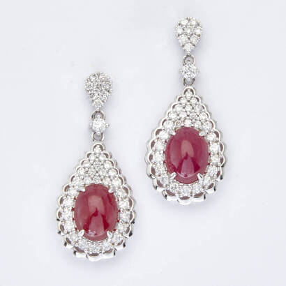 A pair of ruby and diamond drop earrings, two claw set cabochon cut rubies of estimated total weight 7.37 carats, surrounded and accented with seventy-four claw set round brilliant cut diamonds of estimated total weight 1.69 carats in pear cluster motif. 