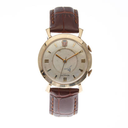 A Gentleman's gold filled wristwatch, Le Coultre, circa 1950s. Case numbered 9386/54019127. Movement numbered 1019702. Alarm function. Circular light gold dial with applied gold batons and Ford logo at 12 o'clock. Dial, case and movement signed. Case back