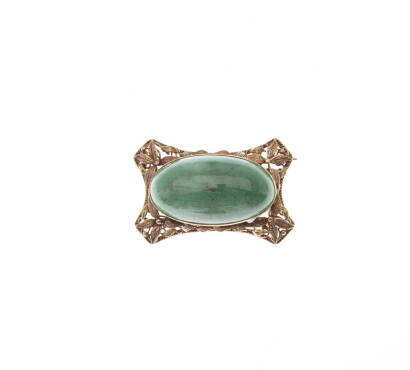 A jadeite and gold brooch, bezel set jadeite cabochon of estimated weight 60.48 carat, in floral motif frame. 9ct gold. Weight 26.9 grams. Length 46mm. Width 31mm. Gemologist's report available.