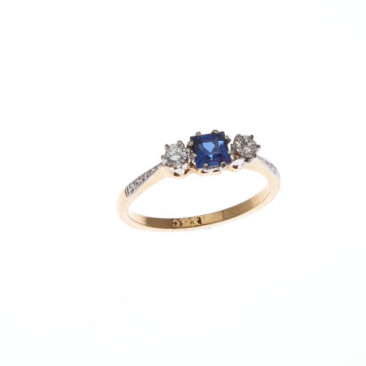 A sapphire and diamond ring, claw set square step cut sapphire centre, round brilliant cut diamond either side with engraved shoulders. 18ct yellow gold. Weight 2.3 grams. Ring size K 1/2.