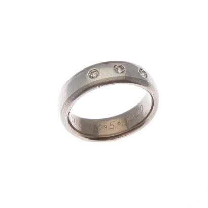 A diamond band ring, three hammer set round brilliant cut diamonds. Platinum and titanium. Weight 5.3 grams. Width 6.0mm. Size M1/2.