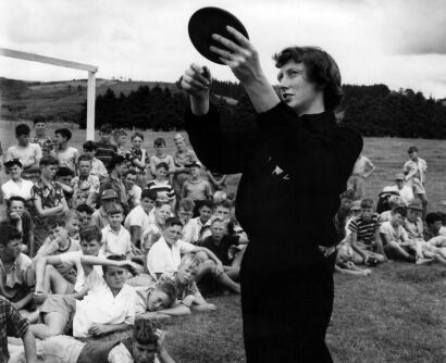 Yvette Williams tips off a group of boys at the Y.M.C.A. camp at Hunua on the finer points of discus throwing, 1955