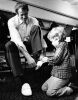 Four-year old Paul Watkinson helps his dad, New Zealand Olympic sculling hopeful Murray, try his Olympic uniform shoes, 1972