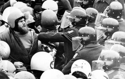 Police officers in riot gear surround a protester outside Lancaster Park