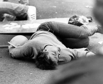 An unconscious protester lies in the street