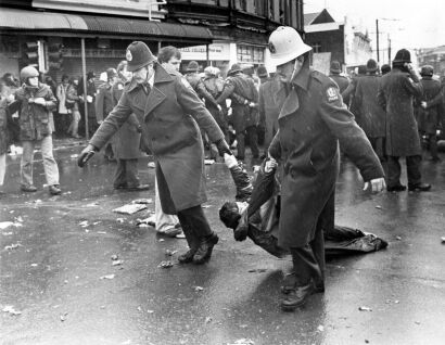 Two police officers drag a protestor down the street during a demonstration