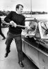 A police officer smashes the side window of a car belonging to a protestor on the Auckland Harbour Bridge