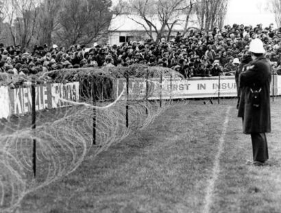 Spectators behind barbed wire watch the Springbok rugby game in Invercargill