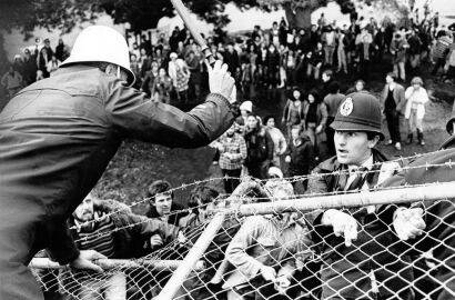 Police officers attempt to keep protesters behind barricades