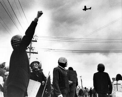 Protesters outside Eden Park salute the airplane as it drops flour bombs onto the field