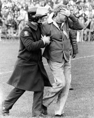 A protester is escorted from the field by a member of the riot squad at Lancaster Park